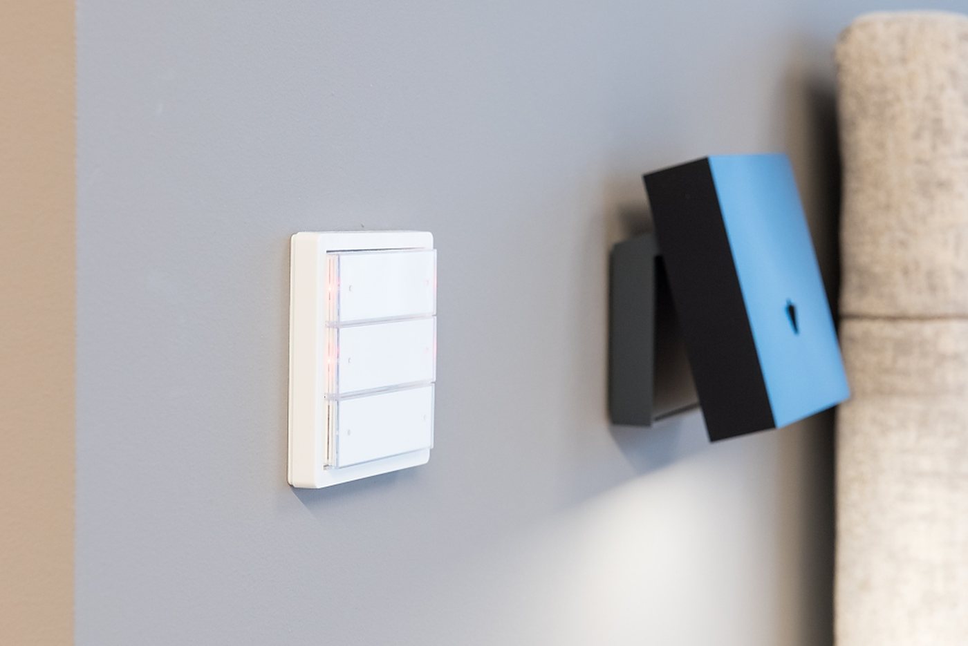 Detail van een schakelaar en een bedieningspaneel op een strak afgewerkte wand