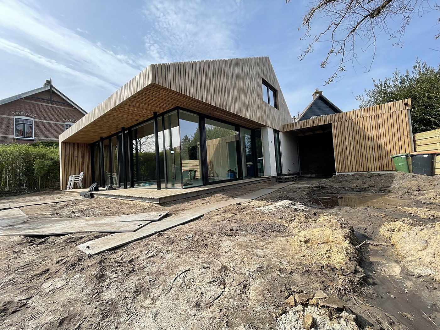 Villa in aanbouw met houten gevelbekleding tijdens de bouwfase